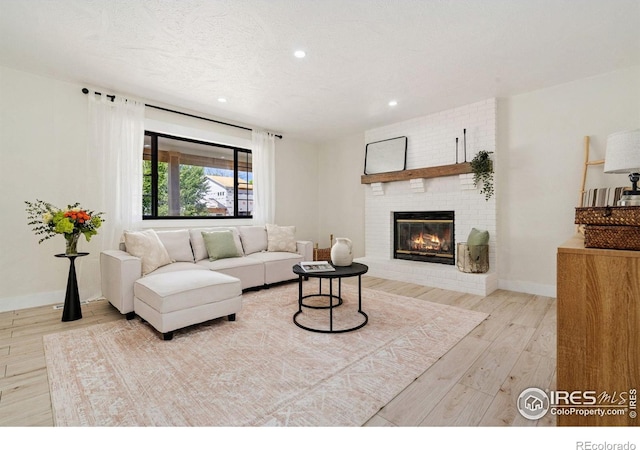 living area featuring wood finished floors, a brick fireplace, recessed lighting, and baseboards