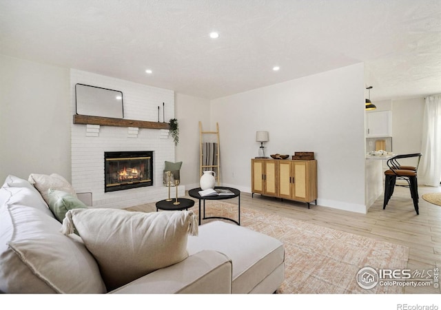 living area featuring light wood-style floors, a fireplace, recessed lighting, and baseboards