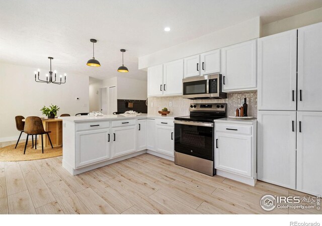 kitchen featuring appliances with stainless steel finishes, a chandelier, a peninsula, tasteful backsplash, and white cabinets