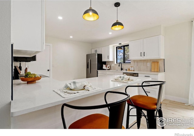 kitchen featuring appliances with stainless steel finishes, a breakfast bar area, a peninsula, a sink, and recessed lighting
