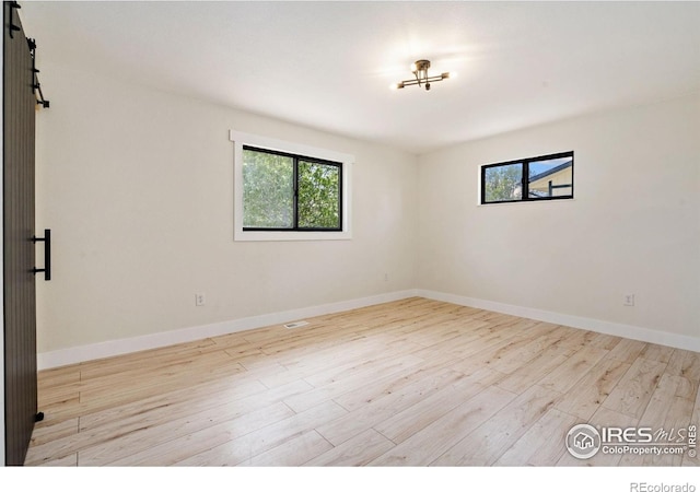 empty room with plenty of natural light, wood finished floors, and baseboards