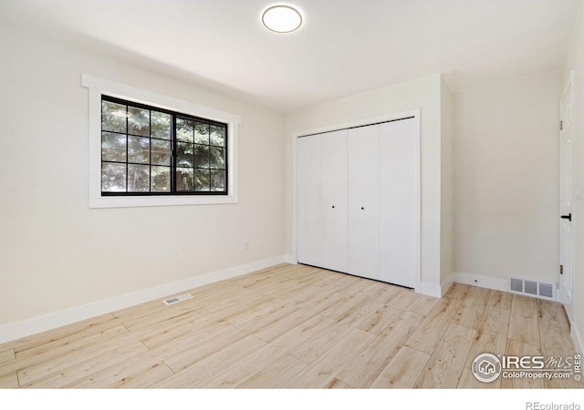 unfurnished bedroom featuring wood finished floors, baseboards, and a closet