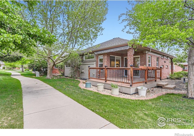 view of front of house with brick siding, a wooden deck, and a front yard