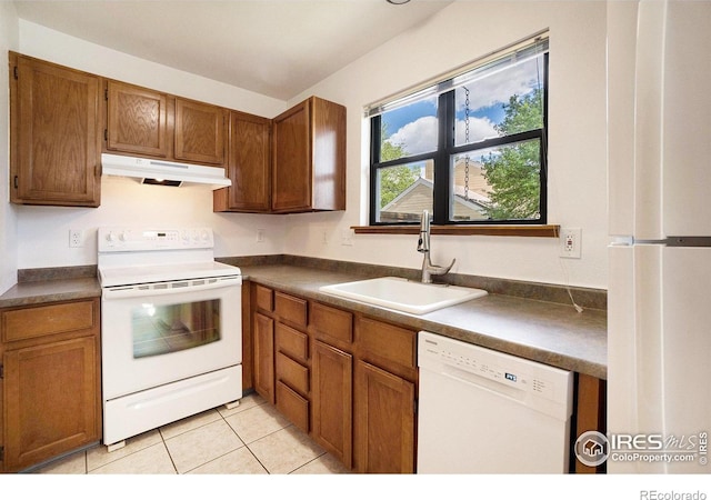 2066 Weathertop Ln, Fort Collins, CO 80526 - kitchen with white appliances, under cabinet range hood, a sink, dark countertops, and brown cabinets