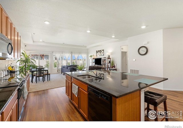 kitchen featuring black dishwasher, a sink, dark countertops, stainless steel microwave, and electric range