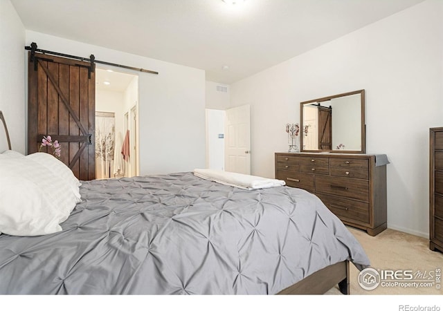 bedroom featuring light colored carpet and a barn door