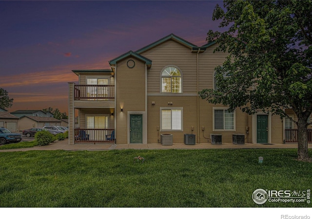 3002 W Elizabeth St Unit G, Fort Collins, CO 80521 - back of house at dusk with a balcony, a lawn, central air condition unit, and a patio