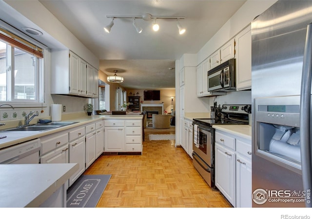 kitchen with stainless steel appliances, a sink, white cabinetry, a peninsula, and open floor plan
