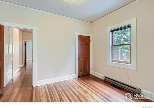 3116 47th St, Boulder, CO 80301 - spare room featuring light wood finished floors, a baseboard radiator, baseboards, and a textured ceiling