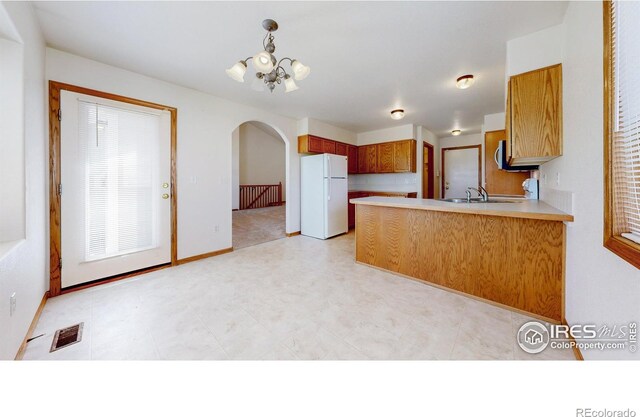 374 Blue Azurite Ave, Loveland, CO 80537 - kitchen with freestanding refrigerator, arched walkways, a chandelier, a peninsula, and light countertops