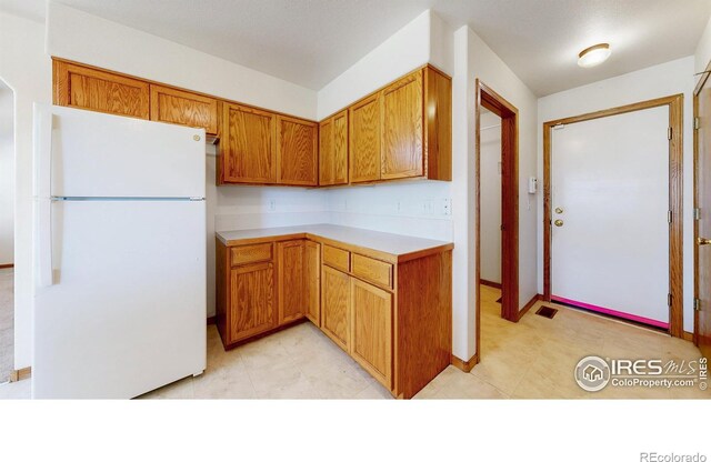 374 Blue Azurite Ave, Loveland, CO 80537 - kitchen with freestanding refrigerator, light countertops, brown cabinets, and light tile patterned floors