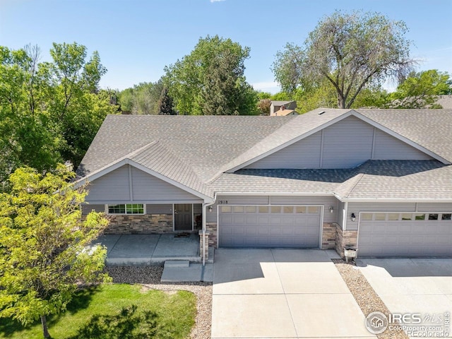 1918 Lily Dr, Loveland, CO 80537 - view of front of house with a shingled roof, a garage, driveway, and stone siding