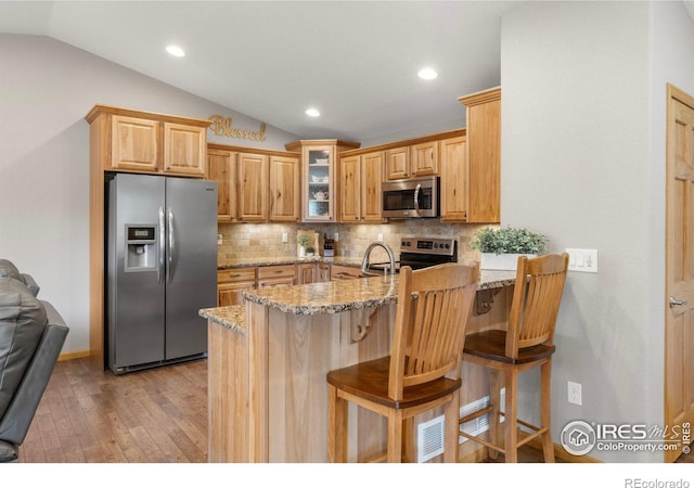 1918 Lily Dr, Loveland, CO 80537 - kitchen featuring stainless steel appliances, lofted ceiling, a peninsula, light wood-type flooring, and glass insert cabinets