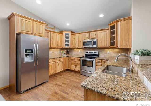 1918 Lily Dr, Loveland, CO 80537 - kitchen with stainless steel appliances, a sink, light wood-style floors, decorative backsplash, and light stone countertops