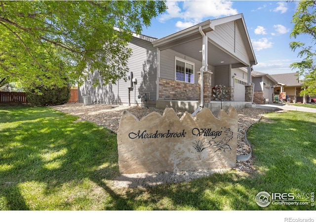 1918 Lily Dr, Loveland, CO 80537 - view of front of house featuring stone siding, an attached garage, driveway, and a porch