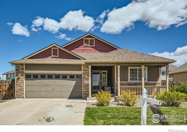 4134 Cypress Ridge Ln, Wellington, CO 80549 - view of front of home with a porch, a garage, concrete driveway, fence, and stone siding