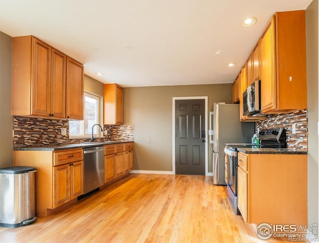 110 Lucerne Dr, Lafayette, CO 80026 - kitchen with appliances with stainless steel finishes, dark countertops, light wood finished floors, backsplash, and recessed lighting