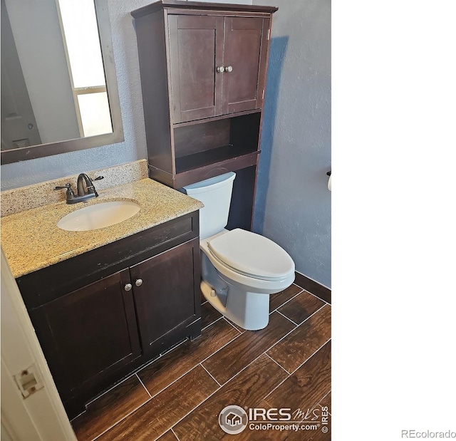 110 Lucerne Dr, Lafayette, CO 80026 - half bathroom featuring wood finished floors, vanity, toilet, and a textured wall