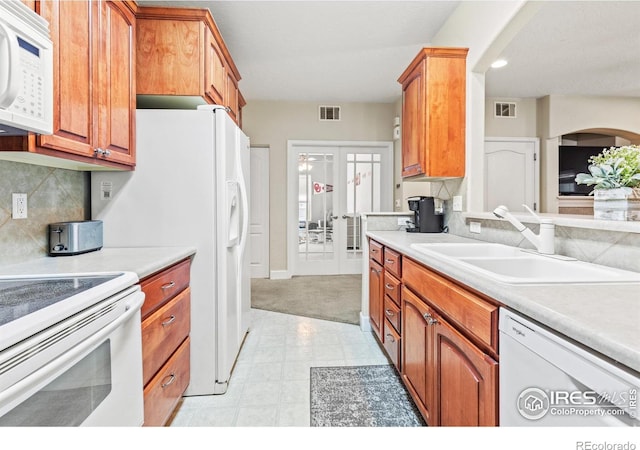 kitchen with white appliances, a sink, french doors, light countertops, and recessed lighting