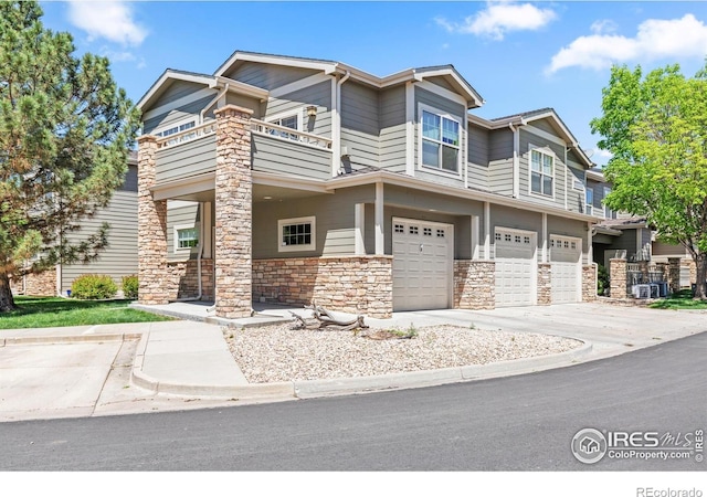 view of front of home with a balcony, a garage, and stone siding