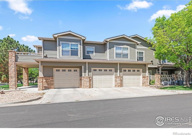 view of front of home featuring a garage, driveway, and stone siding