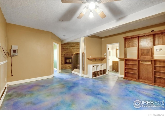 33090 Janelle Cir, Golden, CO 80403 - unfurnished living room featuring ceiling fan, concrete flooring, a brick fireplace, baseboards, and a textured ceiling