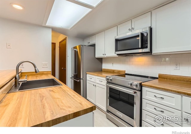 2962 Shadow Creek Dr Unit 306, Boulder, CO 80303 - kitchen featuring wood counters, stainless steel appliances, a sink, tasteful backsplash, and white cabinetry