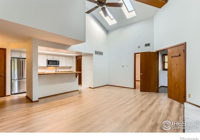 2962 Shadow Creek Dr Unit 306, Boulder, CO 80303 - unfurnished living room with a skylight, high vaulted ceiling, light wood-style flooring, baseboards, and a ceiling fan