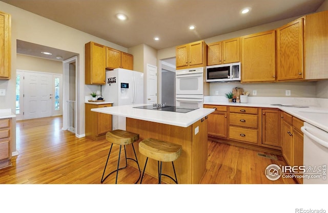 3221 Mesa Verde St, Fort Collins, CO 80525 - kitchen featuring white appliances, light wood-style floors, a kitchen bar, a center island, and recessed lighting