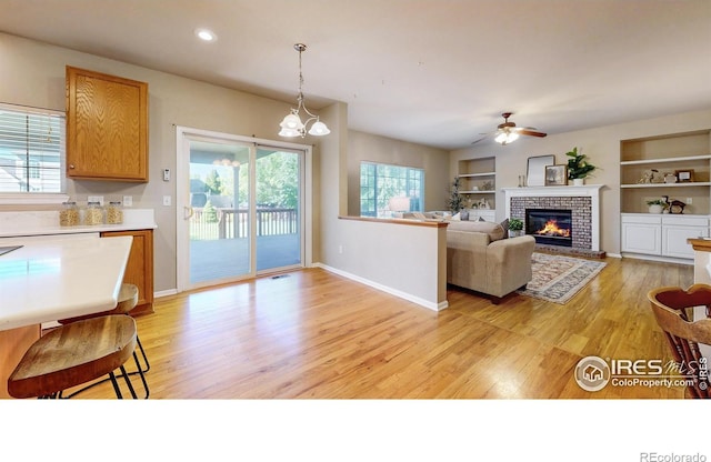 3221 Mesa Verde St, Fort Collins, CO 80525 - living room with light wood finished floors, a fireplace, a ceiling fan, baseboards, and built in shelves