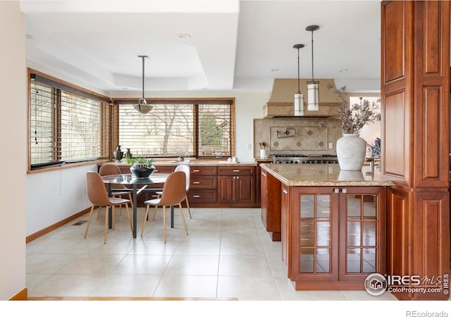 990 Utica Cir, Boulder, CO 80304 - kitchen with tasteful backsplash, light stone countertops, a raised ceiling, glass insert cabinets, and hanging light fixtures