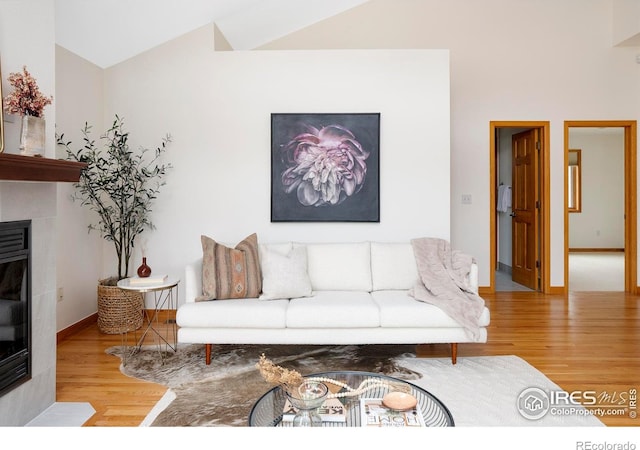990 Utica Cir, Boulder, CO 80304 - living room featuring wood finished floors, lofted ceiling, a glass covered fireplace, and baseboards