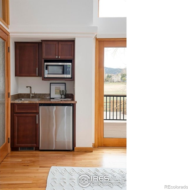 990 Utica Cir, Boulder, CO 80304 - kitchen featuring a sink, stainless steel microwave, light wood-style floors, dishwasher, and dark stone countertops