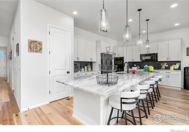 5524 Congressional Ct, Windsor, CO 80528 - kitchen with black microwave, light wood-style floors, backsplash, white cabinets, and recessed lighting