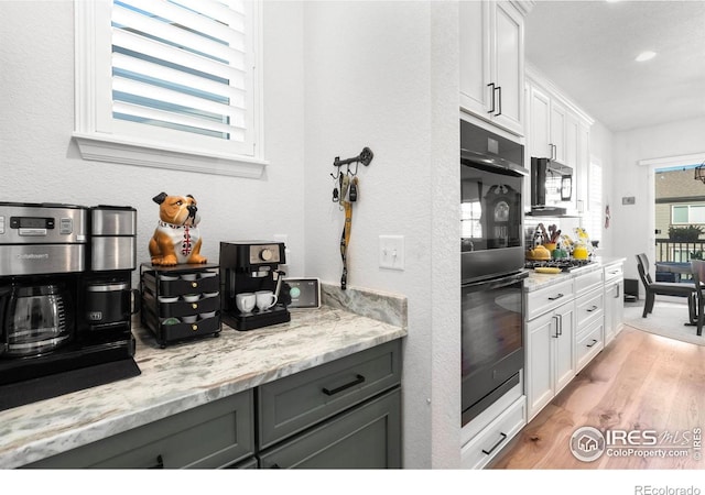 5524 Congressional Ct, Windsor, CO 80528 - kitchen featuring light wood finished floors, white cabinets, light stone counters, and recessed lighting