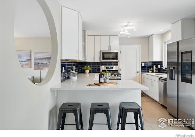 4035 Darley Ave, Boulder, CO 80305 - kitchen featuring appliances with stainless steel finishes, a peninsula, backsplash, a sink, and a breakfast bar