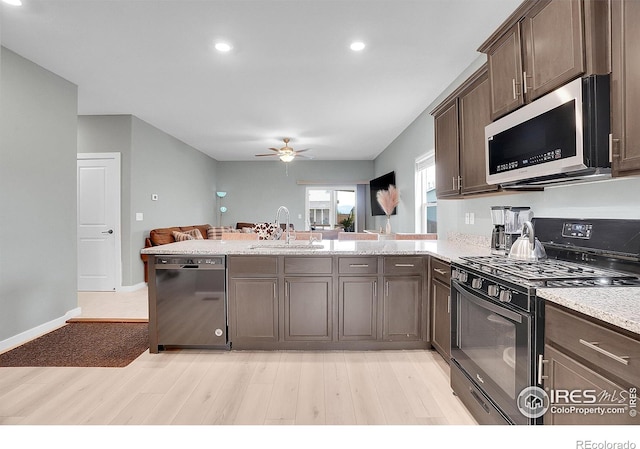 kitchen featuring black appliances, a sink, ceiling fan, light wood-style flooring, and open floor plan
