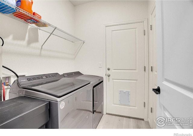 laundry room featuring washer and clothes dryer and light wood finished floors