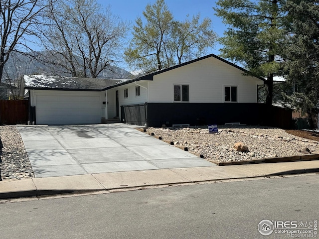 1225 Ithaca Dr, Boulder, CO 80305 - view of front of house featuring an attached garage, concrete driveway, and fence