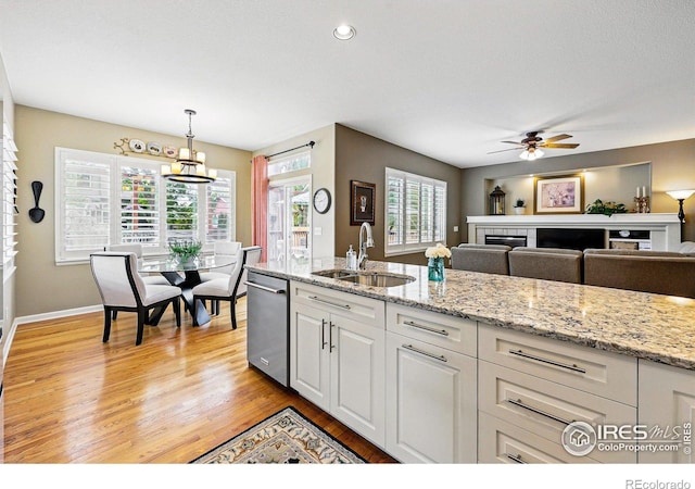 301 Widgeon Ln, Longmont, CO 80503 - kitchen featuring stainless steel dishwasher, a sink, a ceiling fan, light wood-style floors, and white cabinetry