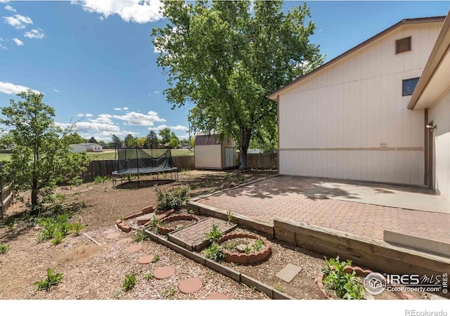 316 43rd Avenue Ct, Greeley, CO 80634 - fenced backyard featuring a trampoline, a storage unit, an outbuilding, and a patio