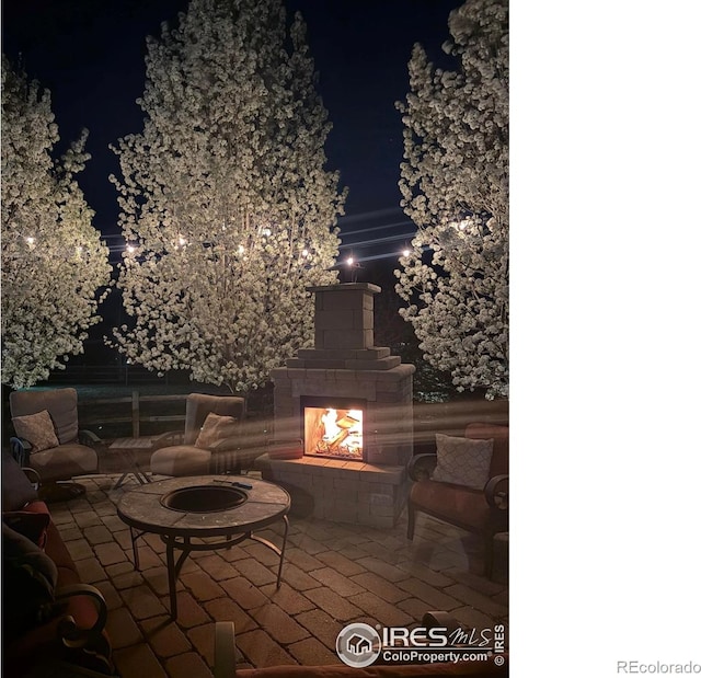 8241 White Owl Ct, Windsor, CO 80550 - patio at twilight featuring a multi sided fireplace and a patio