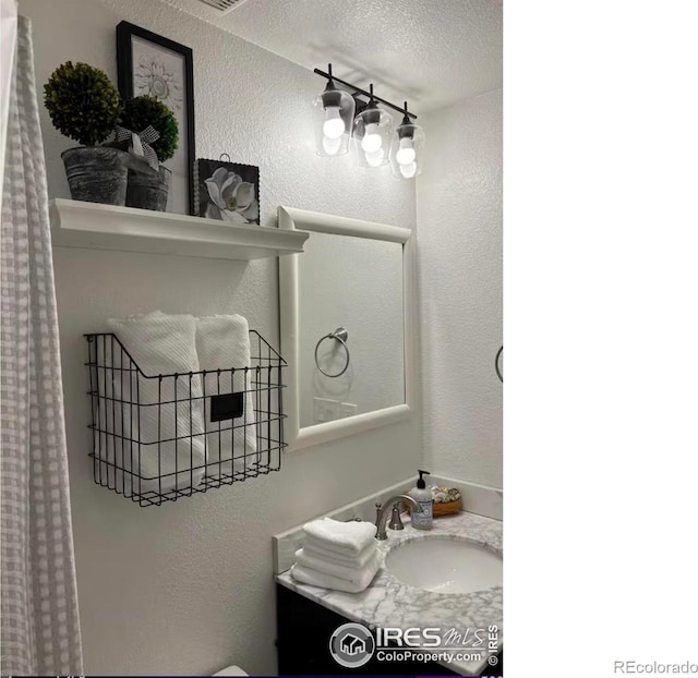 8241 White Owl Ct, Windsor, CO 80550 - bathroom with a textured wall, vanity, and a textured ceiling