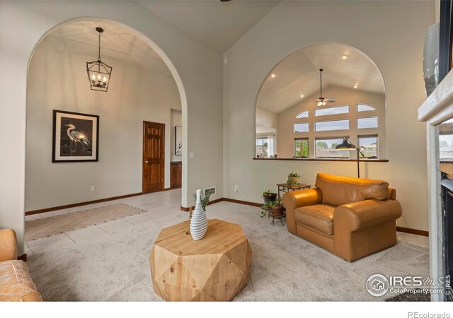 7717 Amour Hill Dr, Greeley, CO 80634 - carpeted living area featuring arched walkways, ceiling fan, baseboards, high vaulted ceiling, and a chandelier