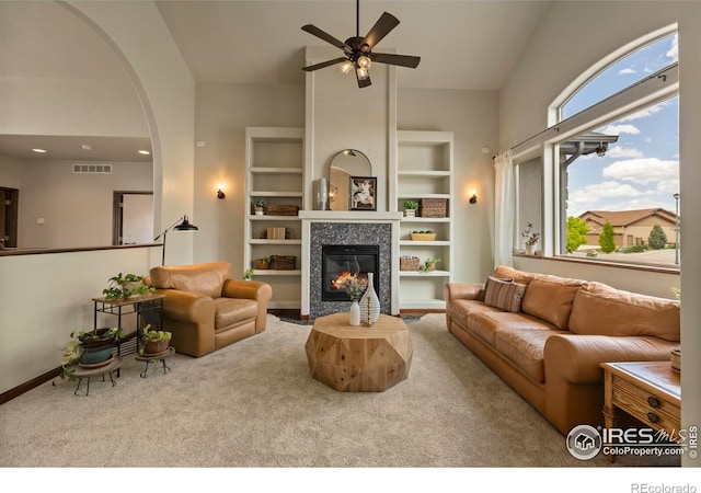 7717 Amour Hill Dr, Greeley, CO 80634 - living room featuring carpet flooring, a ceiling fan, a tile fireplace, high vaulted ceiling, and arched walkways