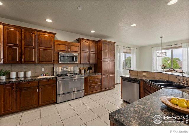 7717 Amour Hill Dr, Greeley, CO 80634 - kitchen with stainless steel appliances, a sink, dark countertops, recessed lighting, and decorative backsplash