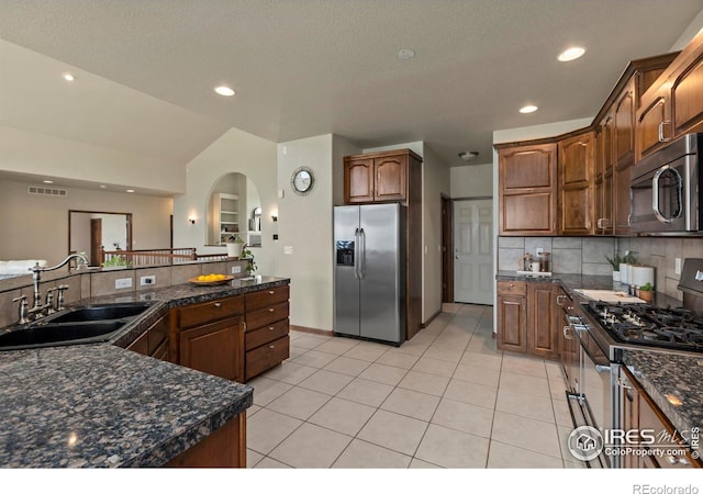 7717 Amour Hill Dr, Greeley, CO 80634 - kitchen with stainless steel appliances, a sink, arched walkways, tasteful backsplash, and light tile patterned floors