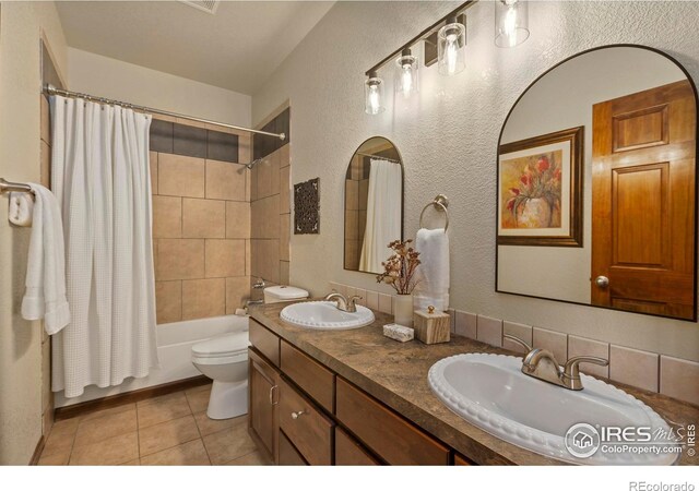 7717 Amour Hill Dr, Greeley, CO 80634 - bathroom featuring toilet, a textured wall, tile patterned floors, shower / bath combo with shower curtain, and double vanity
