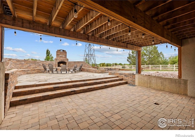 7717 Amour Hill Dr, Greeley, CO 80634 - view of patio / terrace with a warm lit fireplace and fence