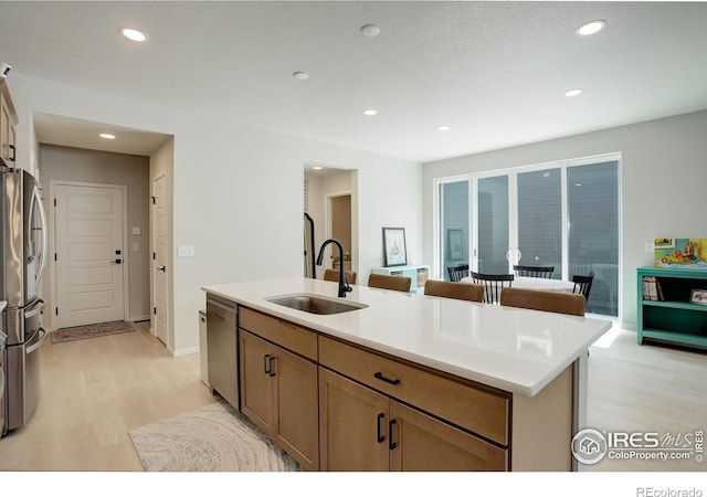 5282 Ribault St, Timnath, CO 80547 - kitchen with a sink, light wood finished floors, appliances with stainless steel finishes, a center island with sink, and recessed lighting
